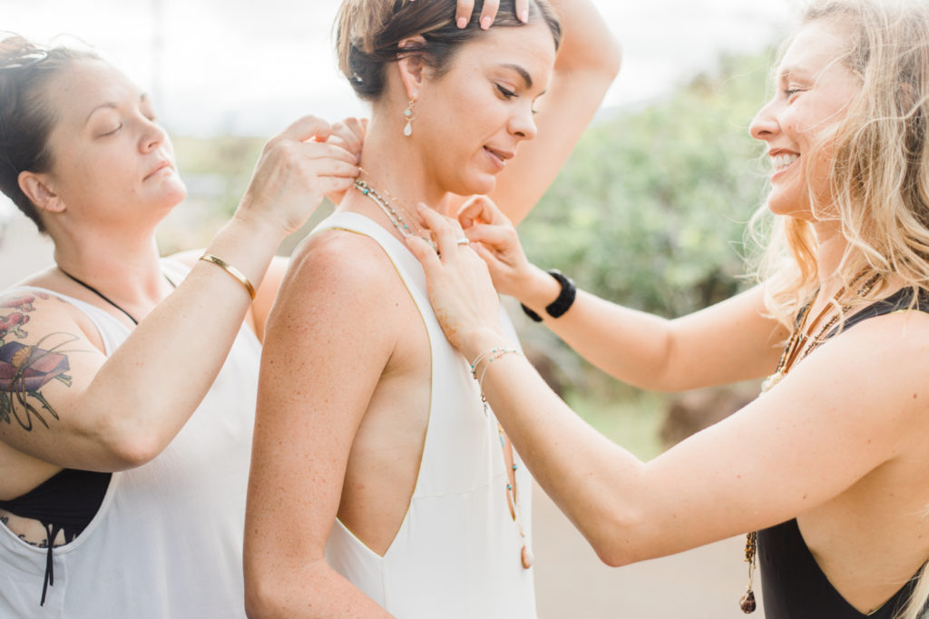 Women putting necklaces on another woman. 