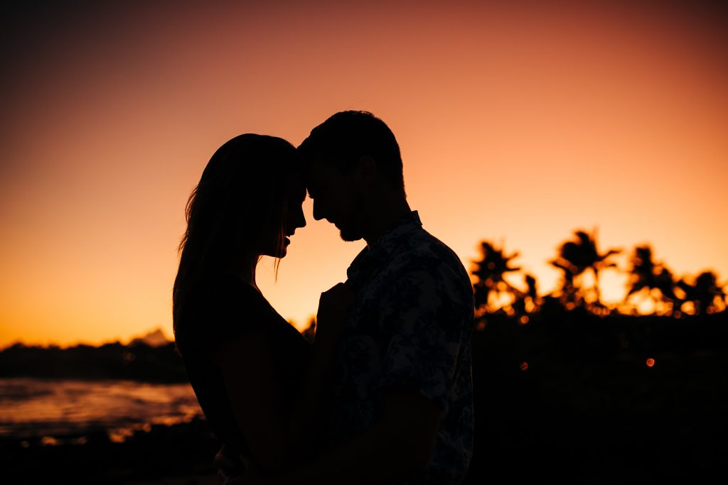 Couple silhouette face to face with orange sunset sky. 