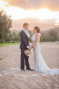 bride and groom on the beach with flower petals in the sand
